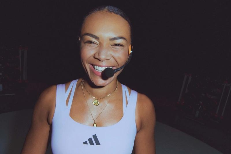 Portrait souriant d'une femme de l'équipe de Webody portant un casque micro et un débardeur Adidas blanc